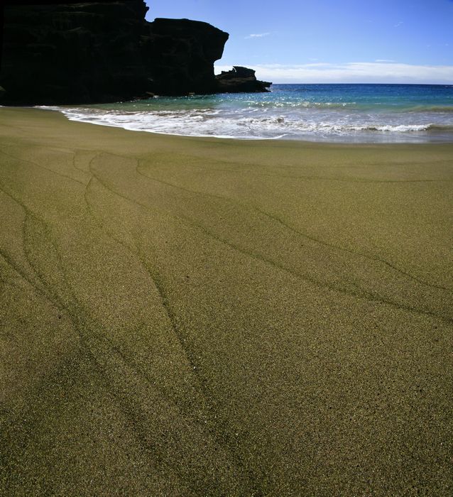 A secluded beach with green sand particles near the southernmost point of the island of Hawaii and of the United States.
