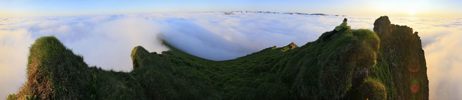 A hiker above the clouds at around 1am on a coastal mountain on the Hornstrandir Peninsula of the Westfiords region of Iceland...