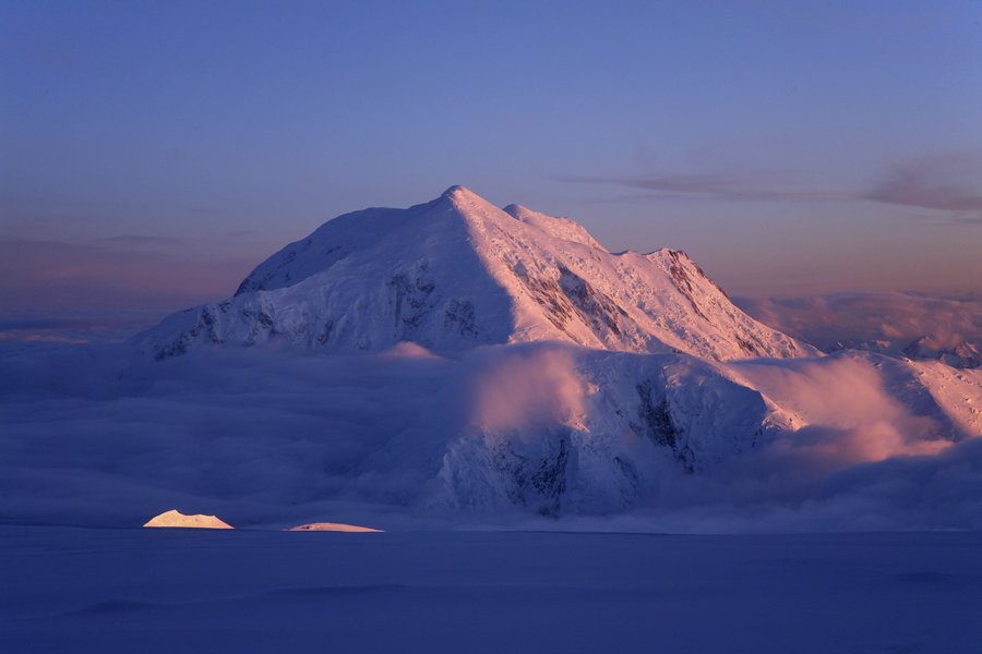 Mt. Foraker above a sea of clouds, lit up by the arctic's midnight sun, as seen from 14,200 ft camp on Denali, Denali National...
